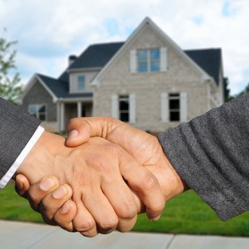Shaking hands in front of a real estate sale
